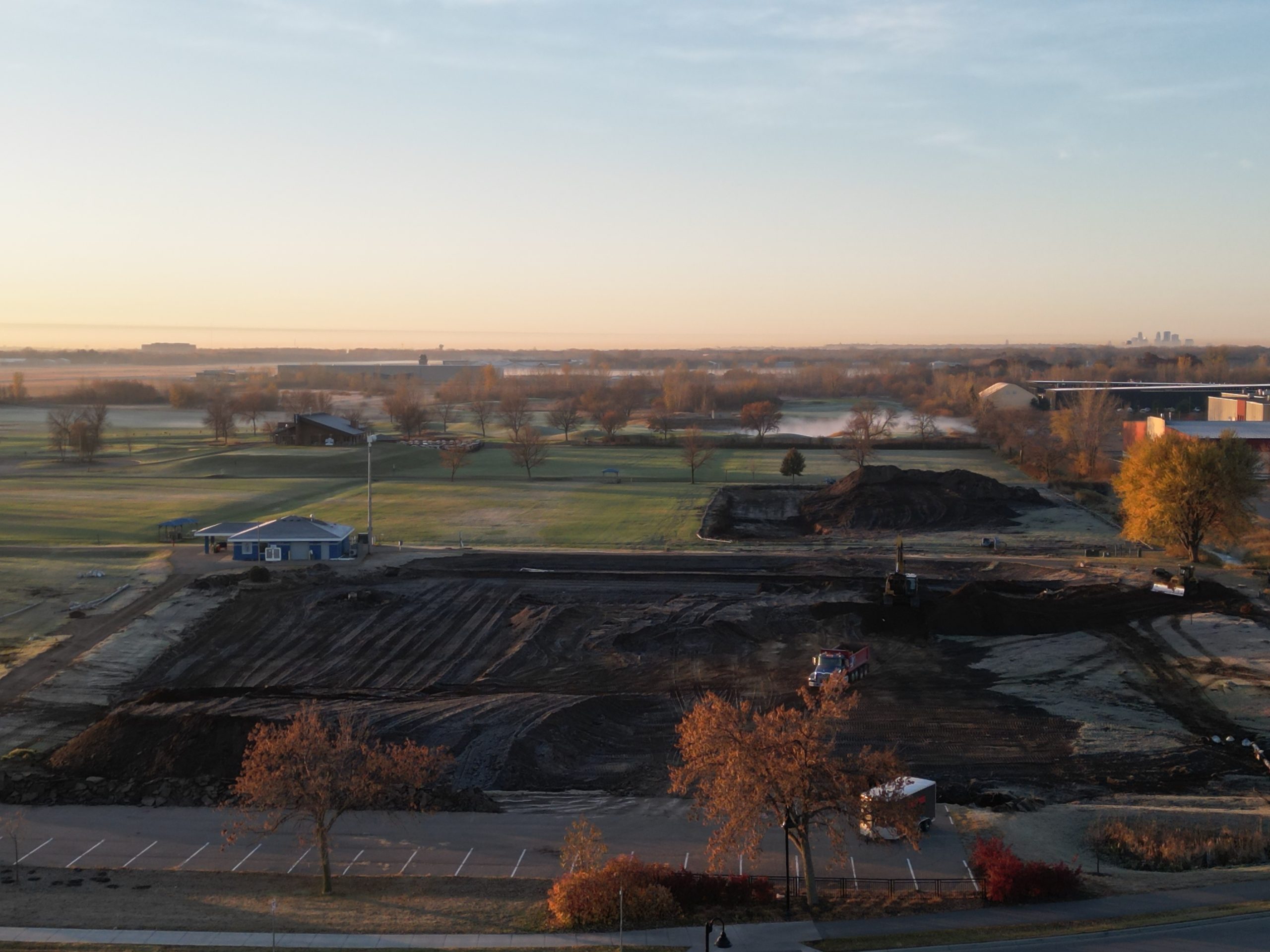 Drone shot of construction on new fields at sunrise, with piles of dirt and no grass