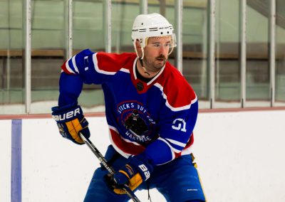 A hockey player in blue and red gear on the ice, preparing to pass or shoot.